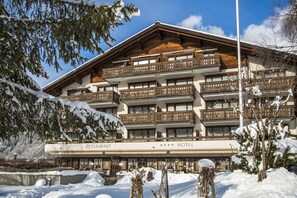 Un hotel de varios pisos con balcones, un restaurante y paisajes nevados.