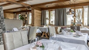 A restaurant with wooden beams, white tablecloths, and grey upholstered chairs. - Sunstar Hotel Klosters (Klosters-Serneus)