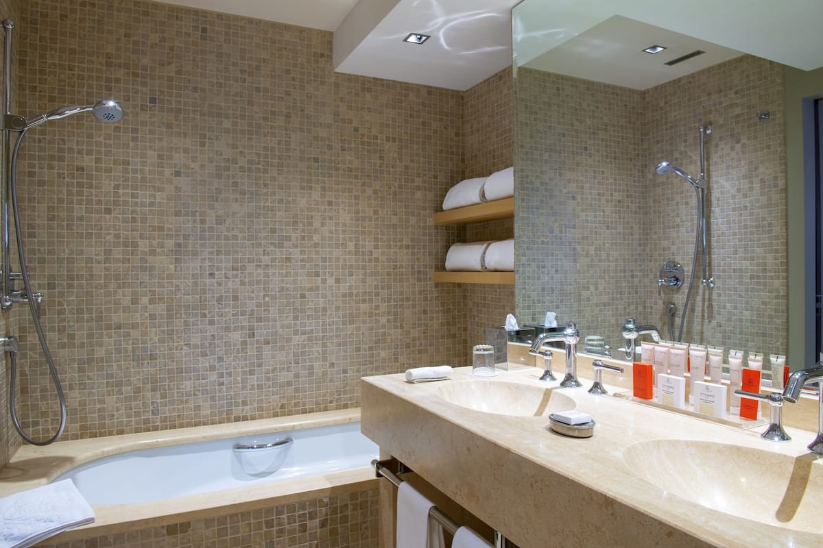 deluxe room | bathroom | rainfall showerhead, designer toiletries, hair dryer, bathrobes