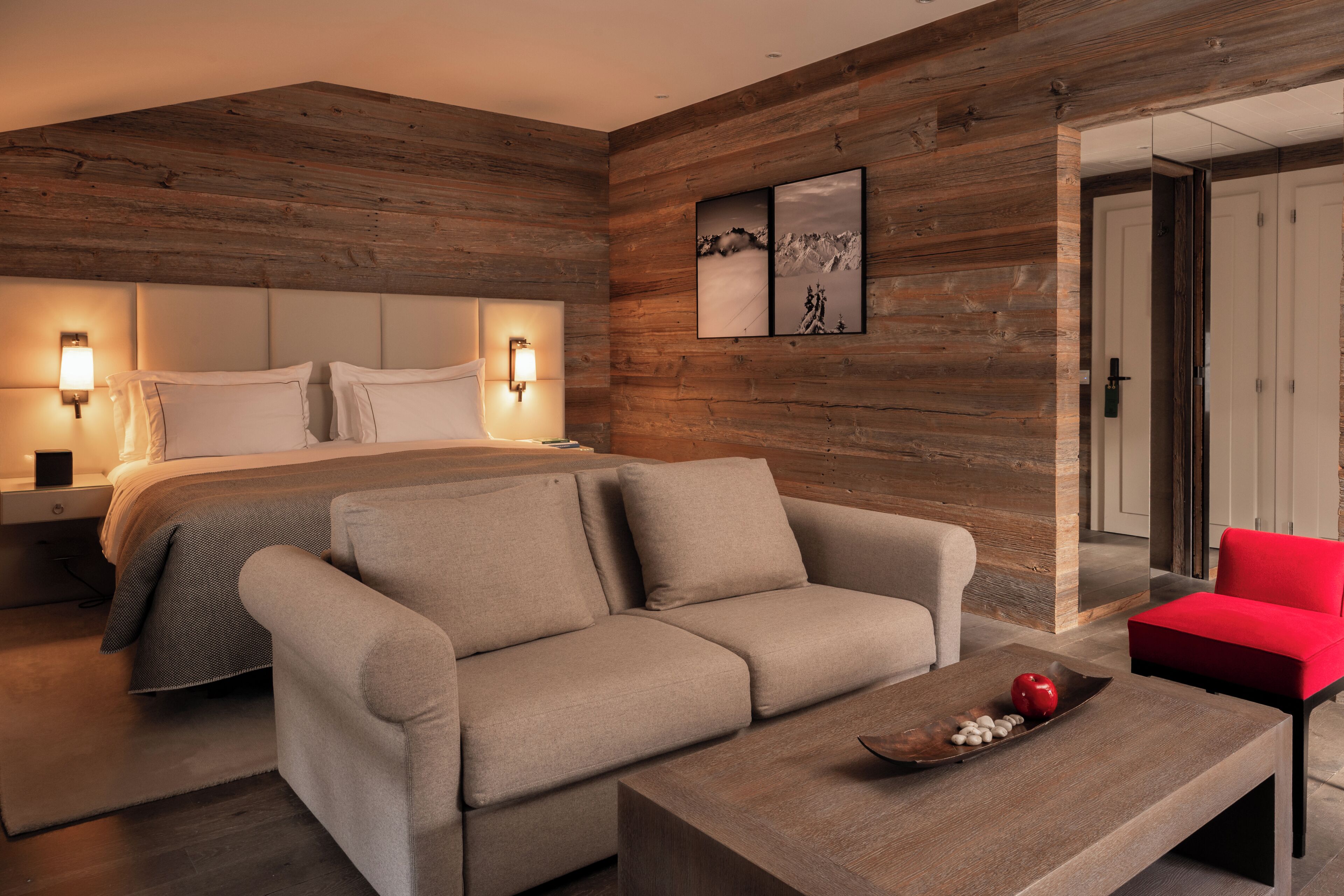 Un dormitorio moderno con una cama, un sofá, una mesa de centro y una silla roja.