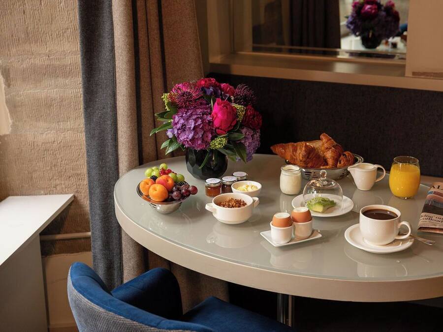A breakfast table with croissants, fruit, coffee, and juice.