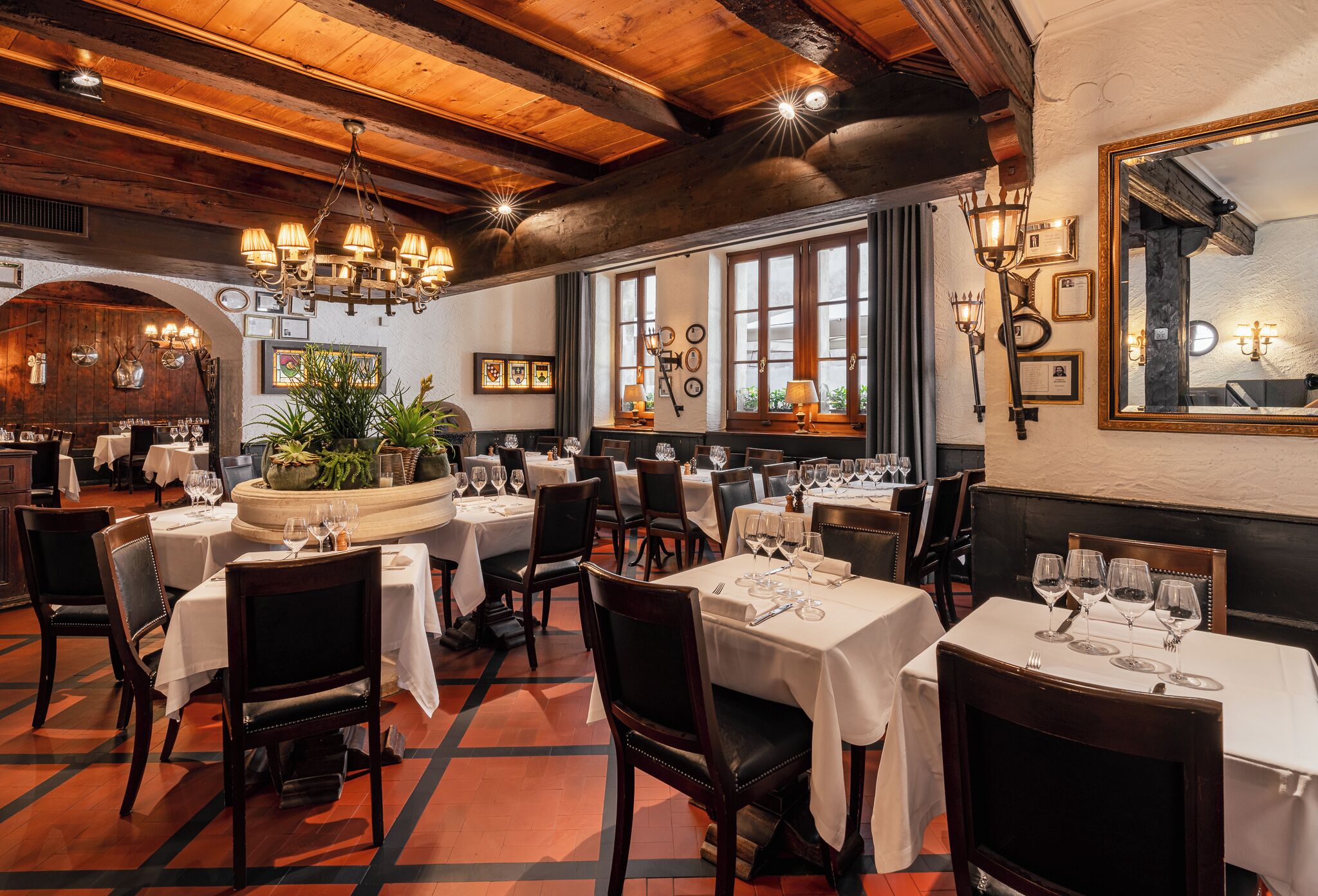 Een restaurantinterieur met meerdere eettafels, stoelen en verschillende soorten verlichting.