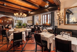 Un interior de restaurante con varias mesas, sillas y diferentes lámparas.