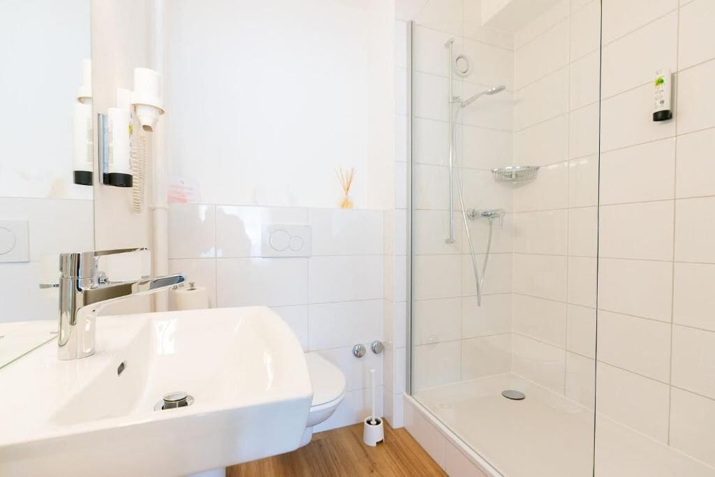Een moderne badkamer met een wit wastafelmeubel, toilet en douchecabine met glazen wanden.
