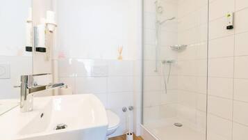 Een moderne badkamer met een wit wastafelmeubel, toilet en douchecabine met glazen wanden.