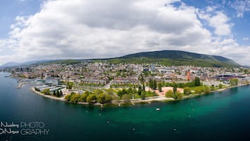 Ein Luftbild einer Küstenstadt mit Hafen, Gebäuden und einer Hügelkulisse im Hintergrund.