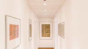 A hallway with framed artworks on the walls and a wooden floor. - Hotel des Arts (Neuchatel)