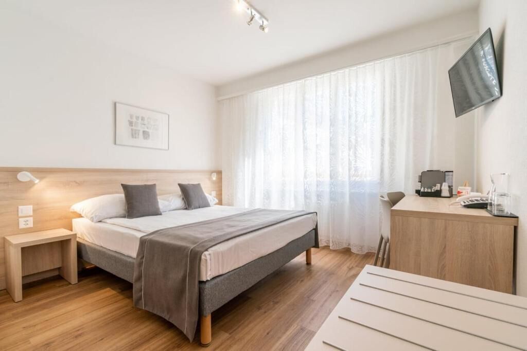 Una habitación de hotel moderna con una cama de madera, una mesita de noche y un escritorio con una silla.