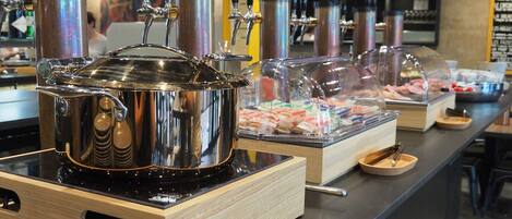 A buffet setup with a stainless steel pot and multiple beverage dispensers.