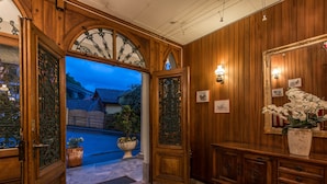 A wooden interior with a large mirror, a potted plant, and a door leading outside. - Hôtel Masson (Veytaux)