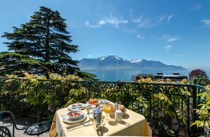 A table set with breakfast items overlooking a mountain and lake. - Hôtel Masson (Veytaux)