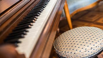 Een close-up van een piano met een gestreept krukje ervoor.