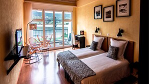 A hotel room with two beds, a desk, a chair, and a balcony with a view of the outdoors. - Hôtel Bellevue Le Rocheray (Le Chenit)