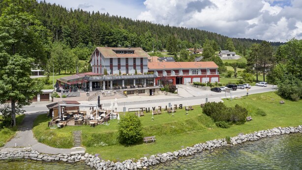 A lakeside hotel with outdoor seating, a restaurant, and a view of the lake. - Hôtel Bellevue Le Rocheray (Le Chenit)