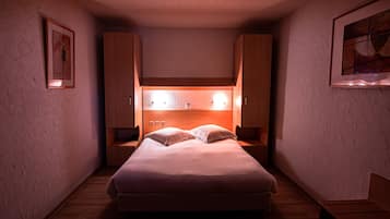 A small, cozy bedroom with a bed, nightstands, and wooden cabinets.
