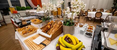 A buffet table with various food items and decorative flowers.