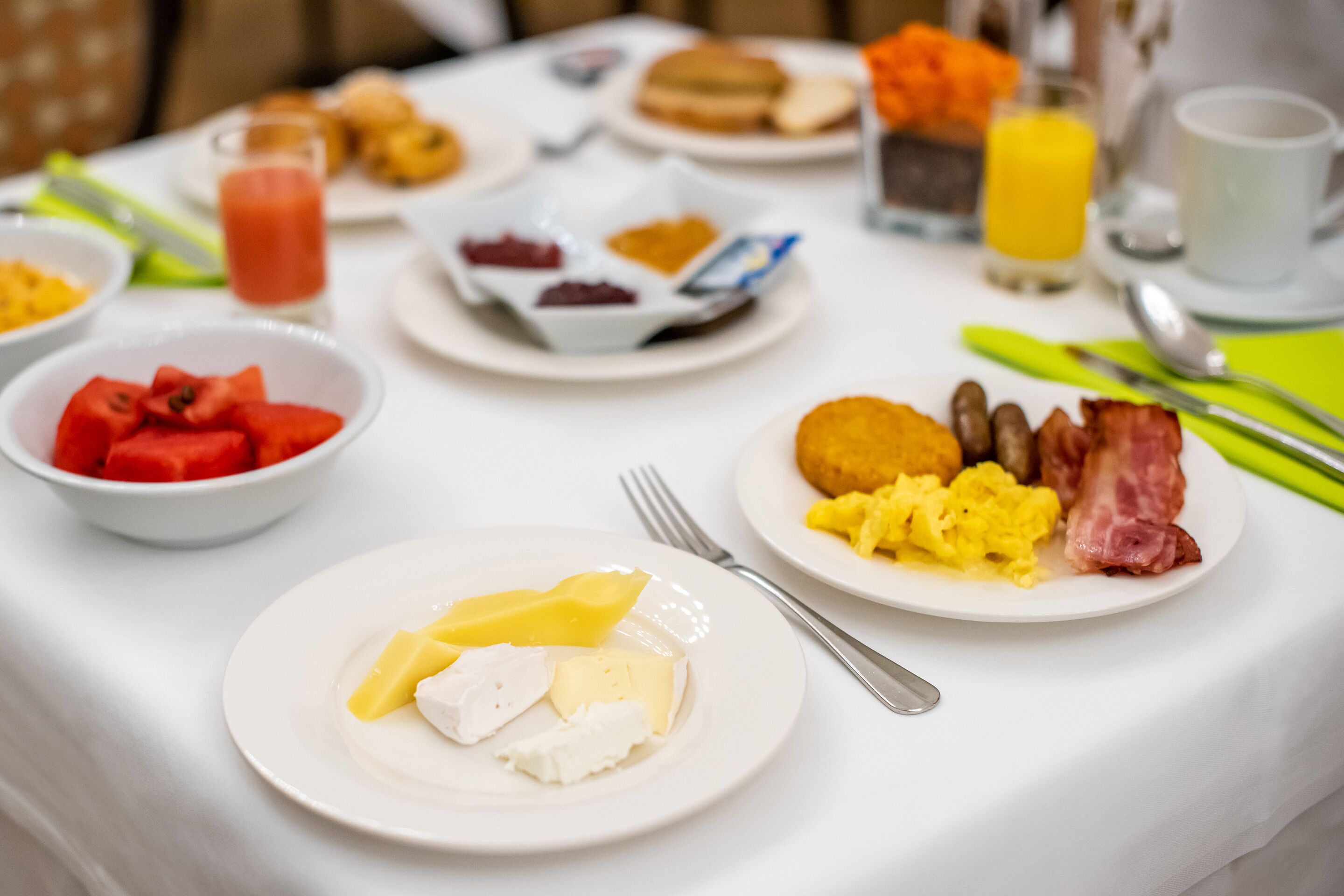 Une table de petit-déjeuner avec divers plats, notamment des œufs, du bacon, des toasts et des fruits.