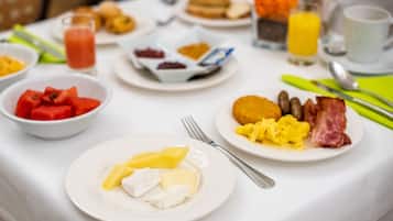 Une table de petit-déjeuner avec divers plats, notamment des œufs, du bacon, des toasts et des fruits.