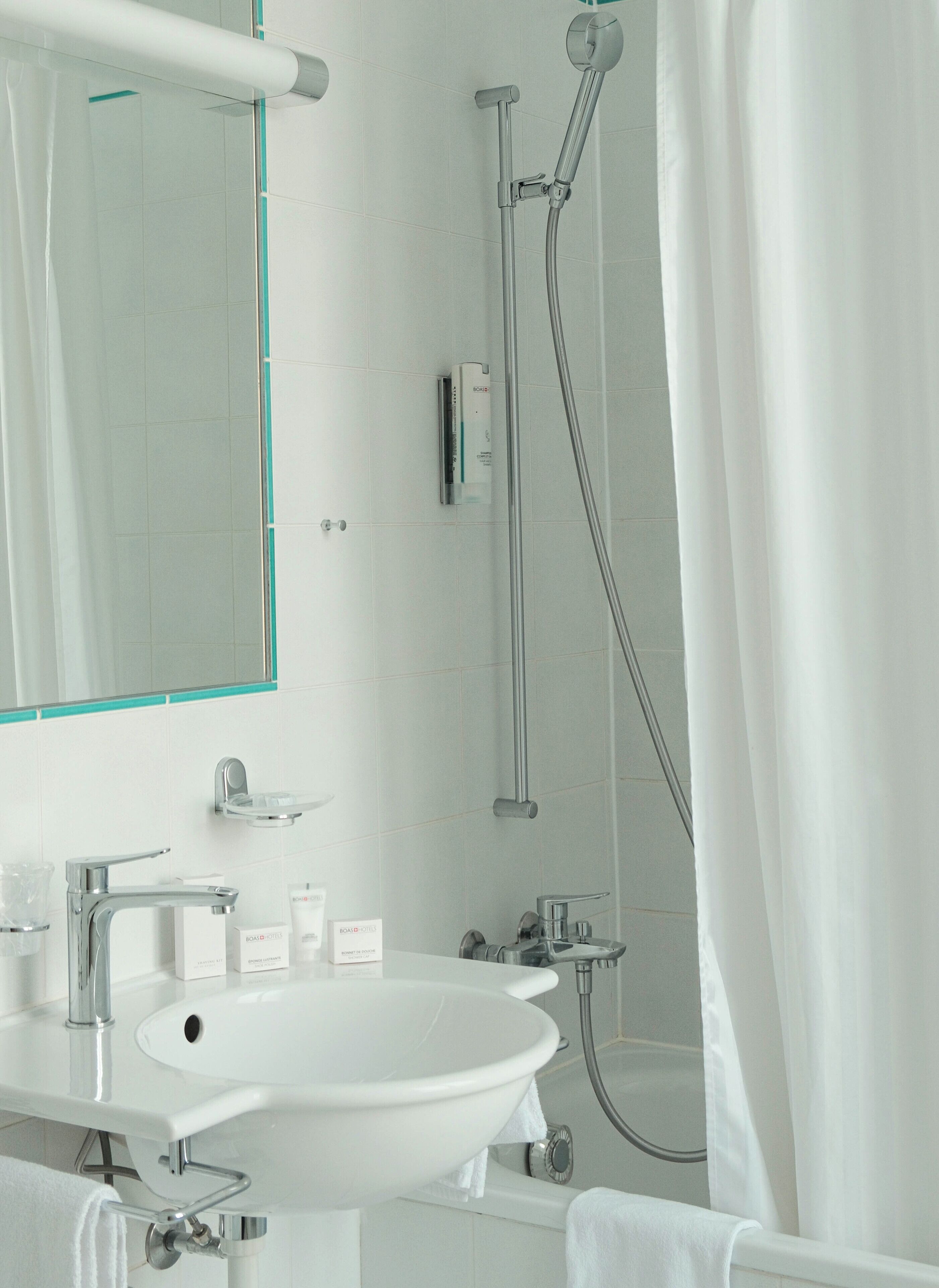 Un baño moderno con lavabo blanco, espejo y ducha.