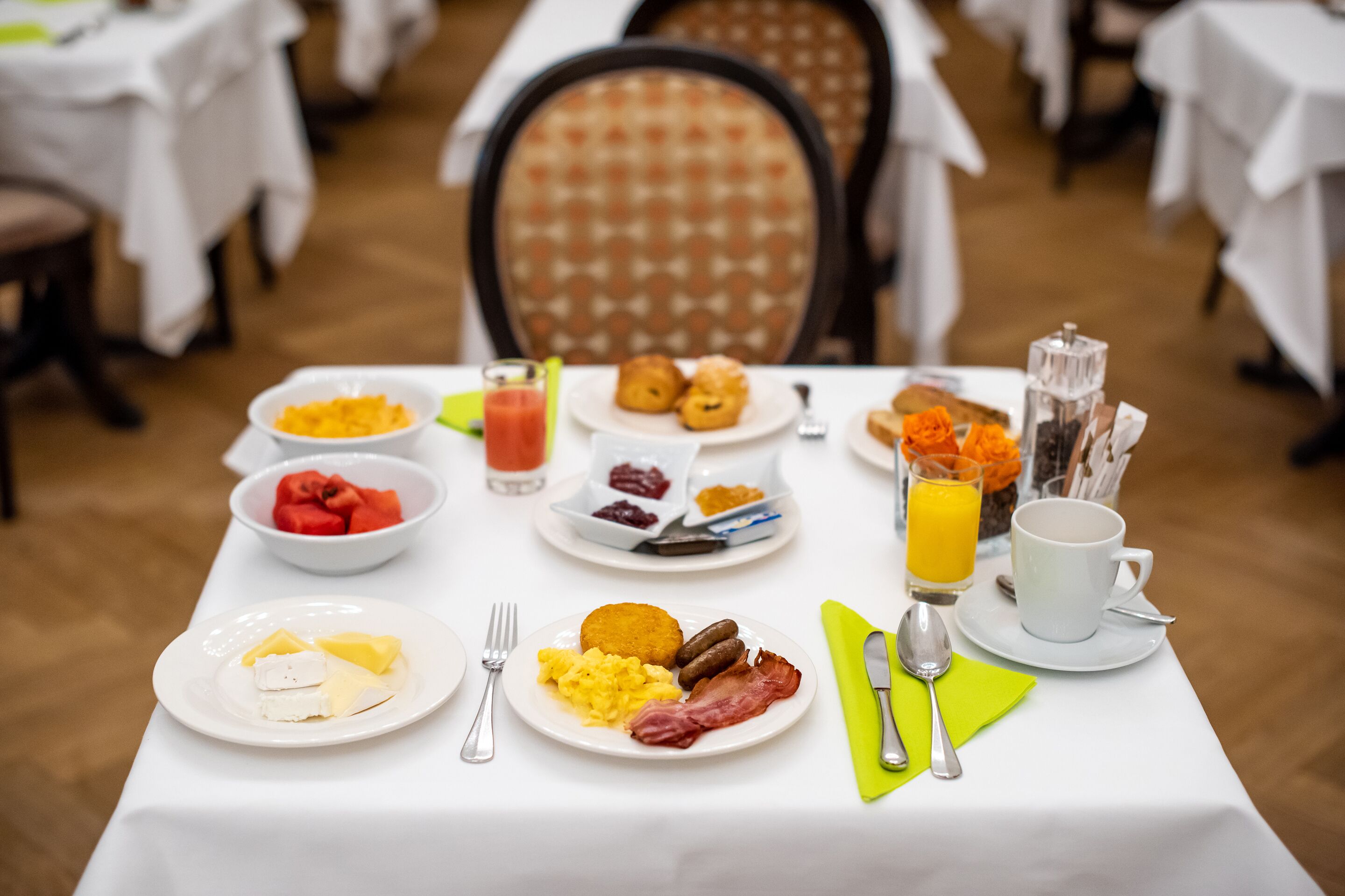 Ett frukostbord med tallrikar fulla av mat, ett glas apelsinjuice och en kopp kaffe.