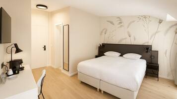 Une chambre à coucher comprenant un lit, des tables de chevet, un bureau avec une chaise et un miroir.