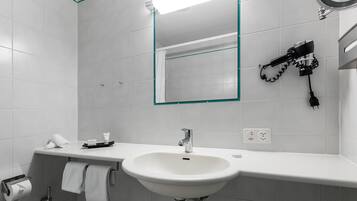 A modern bathroom with a white sink, a mirror, and a hairdryer mounted on the wall.
