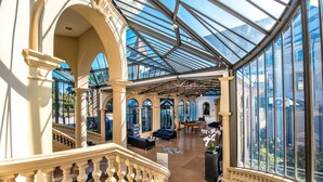 Un amplio atrium con techo de vidrio, una escalera monumental y un área de descanso con sofás.
