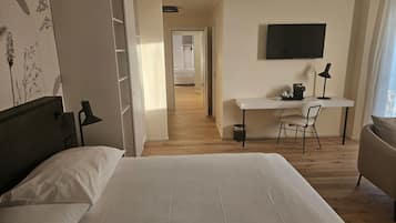 Une chambre d’hôtel avec un lit, un bureau et une chaise, une télévision et une fenêtre.