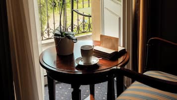 Ein Zimmer mit Tisch, Stuhl, Topfpflanze und Fenster mit Blick auf Grünflächen.