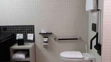 A modern bathroom with a white toilet, a black bathtub, a towel rack, and a hand dryer.