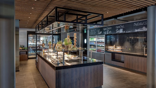A modern kitchen area with a central island, glass display cases, and a chalkboard menu.