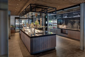 Un área de cocina moderna con una isla central, vitrinas de vidrio y un menú en una pizarra.