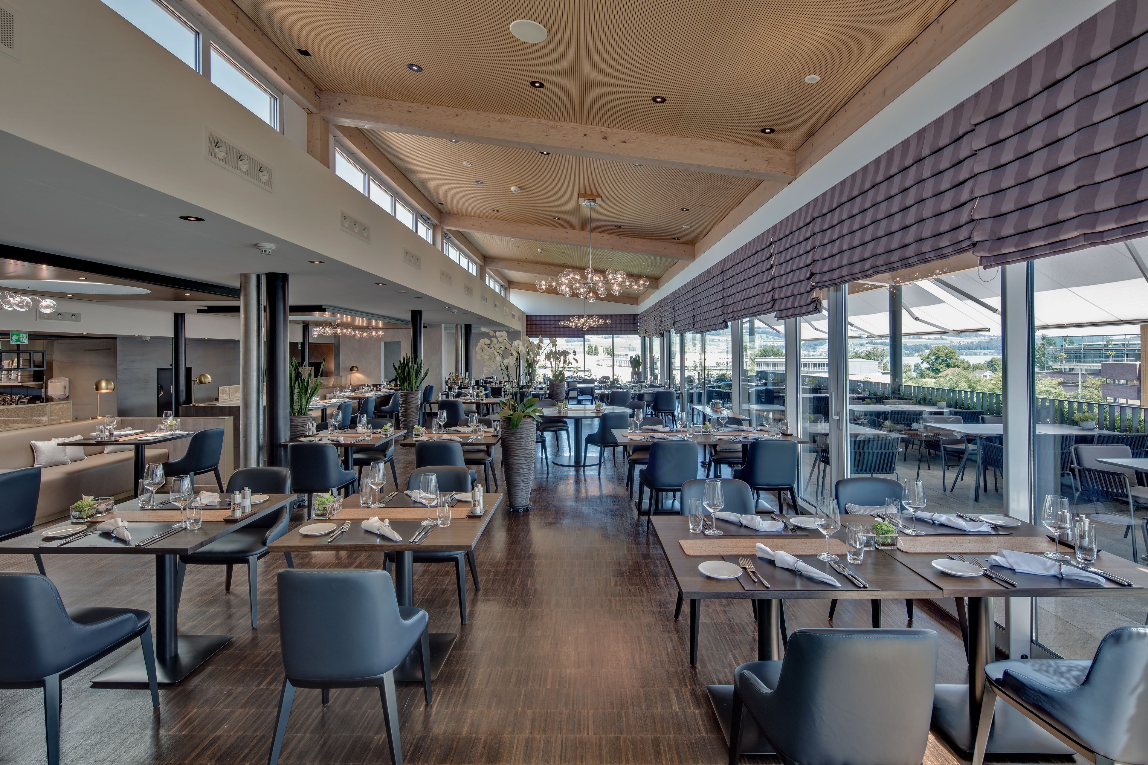 A spacious restaurant with high ceilings, large windows, and modern decor.