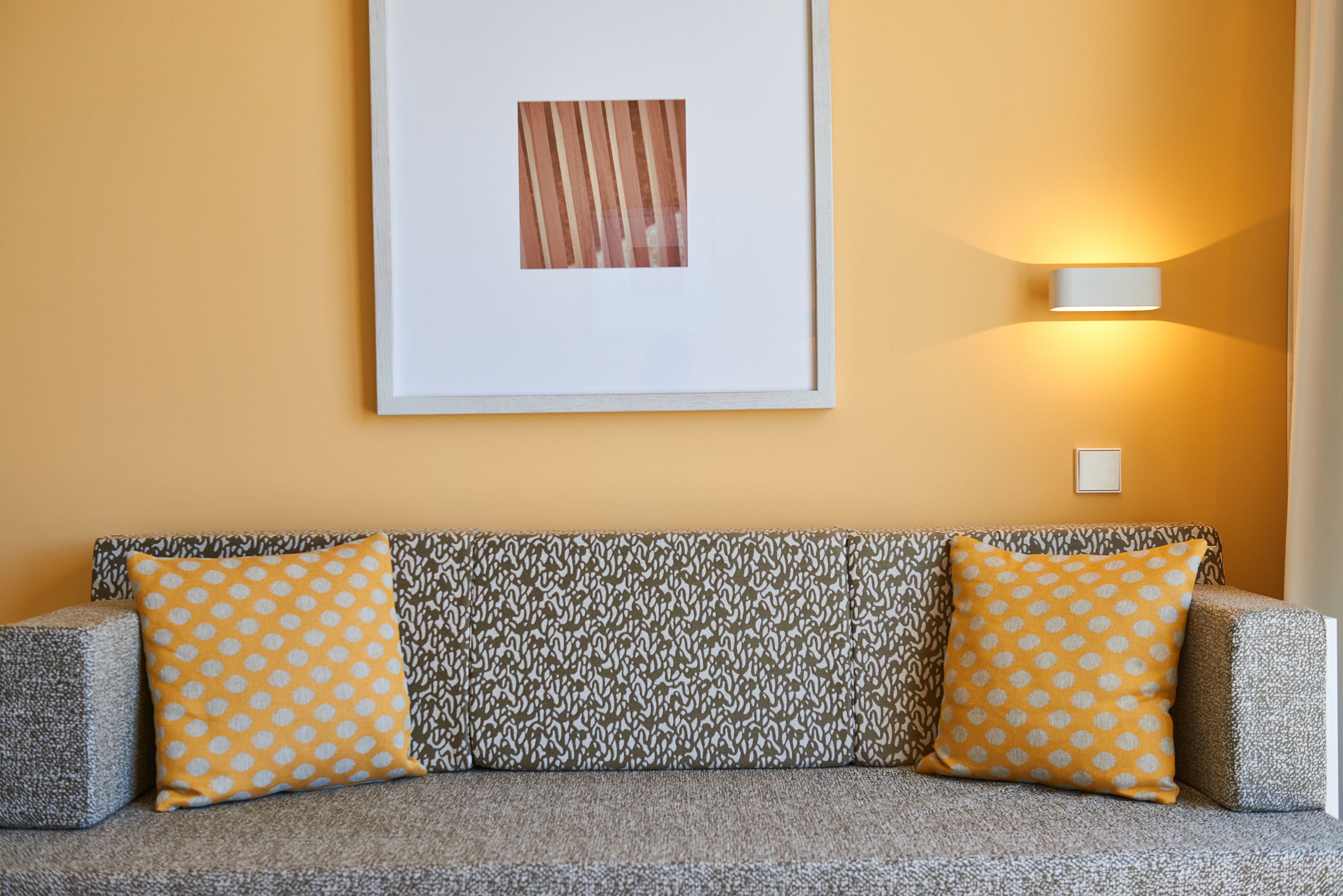 A sofa with patterned cushions and a framed artwork on the wall.