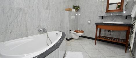 A bathroom with a bathtub, toilet, sink, and mirror.