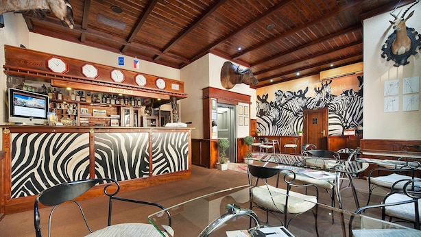 Un restaurante con una pared a rayas de cebra, techo de madera y una zona de bar con relojes.