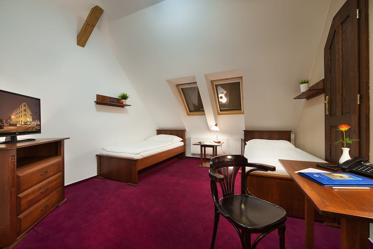 Une chambre d’hôtel de taille réduite, comprenant un lit, un bureau, une chaise, une télévision et une petite fenêtre.