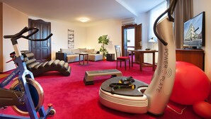 Un gimnasio en casa con equipo de ejercicio, un sofá y una zona de comedor.