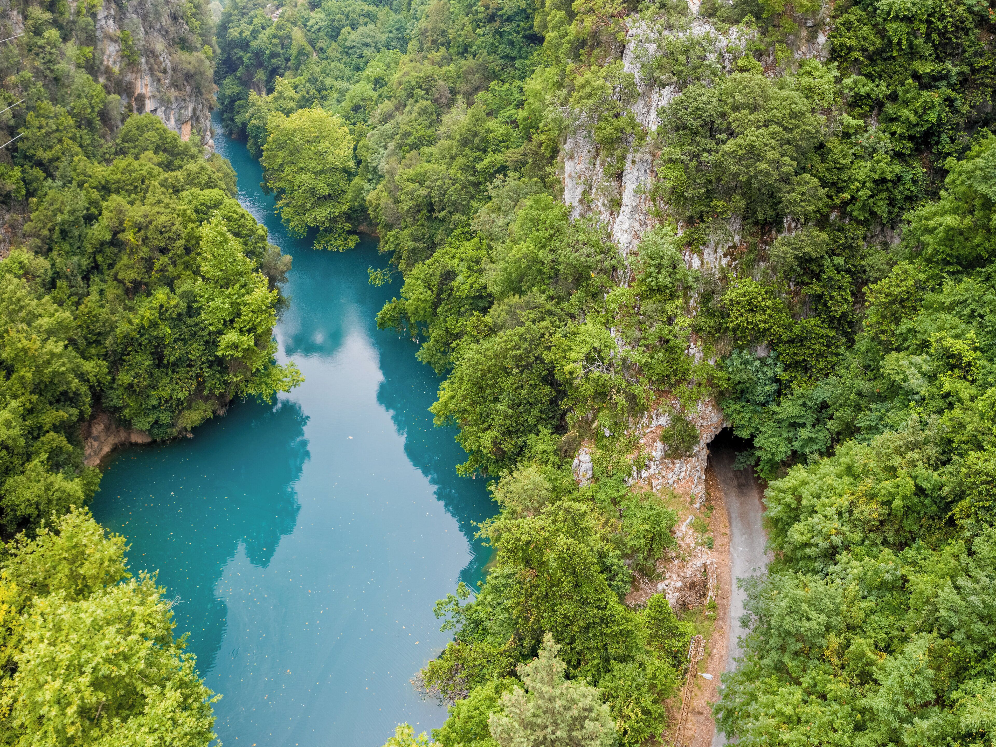 A river winding through a forested gorge with a narrow road alongside.