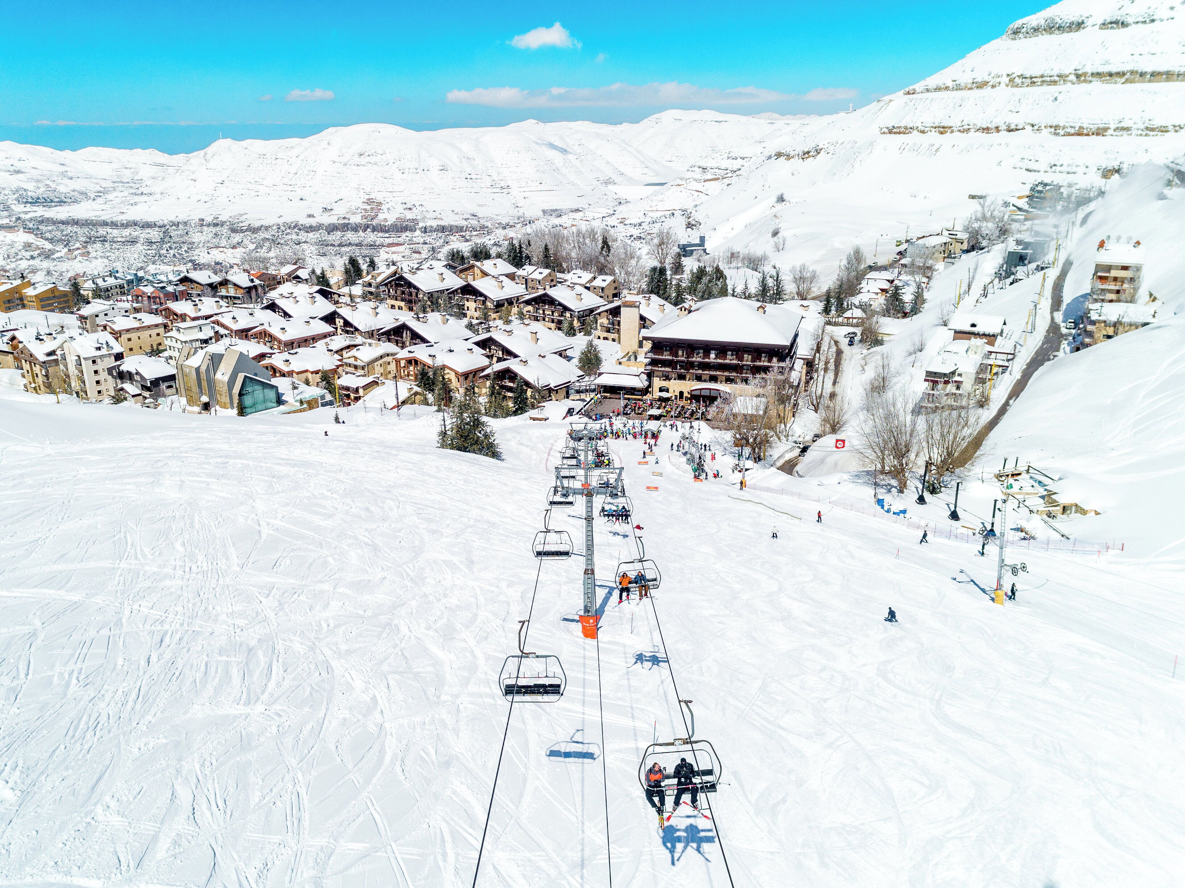 A ski resort with multiple buildings, a ski lift, and a snowy landscape.