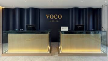 Una recepción con una pared azul oscuro y el texto "VOCO AN IHG HOTEL".
