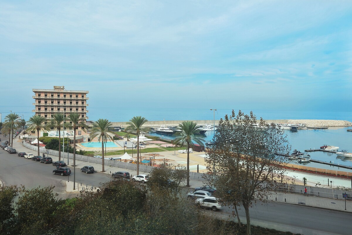 A coastal area with a parking lot, a building, and a marina with boats.