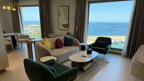 A modern living room with a sofa, two armchairs, a coffee table, and a view of the ocean. - voco Beirut Central District by IHG (Beirut)