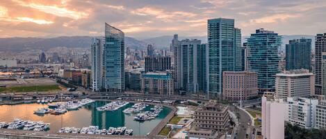 A marina with numerous boats docked, surrounded by modern high-rise buildings and a cityscape in the background.