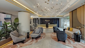 A modern hotel lobby with a reception desk, seating area, and decorative lighting. - voco Beirut Central District by IHG (Beirut)