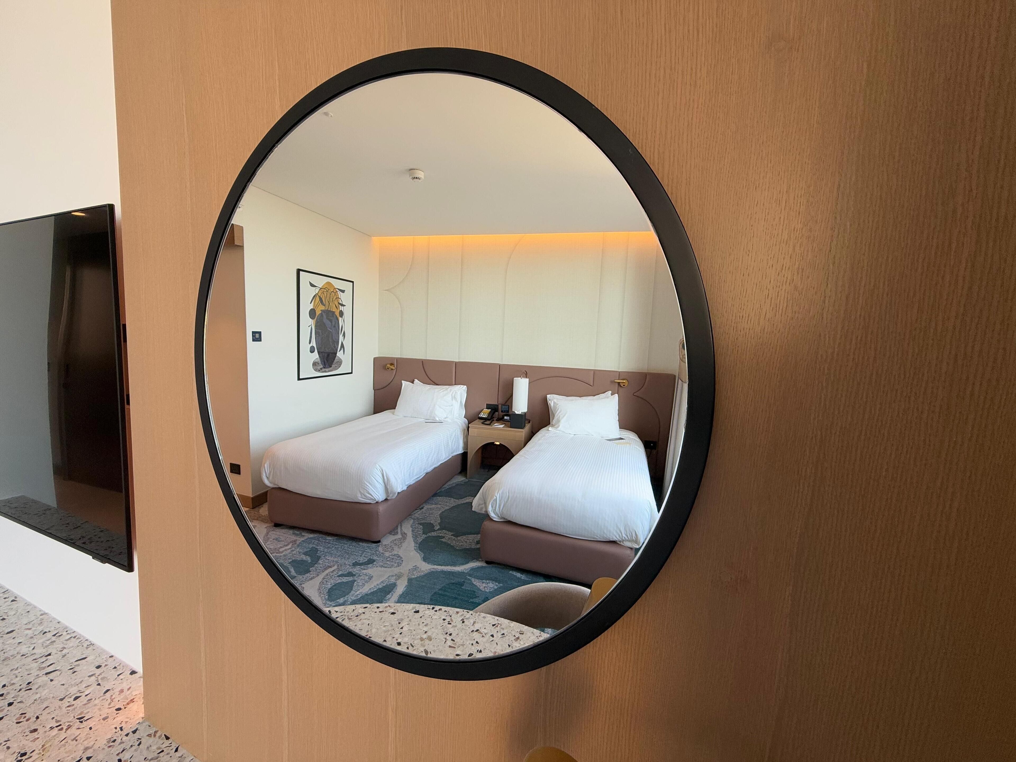 A hotel room with two beds, a TV, a painting, and a carpeted floor.