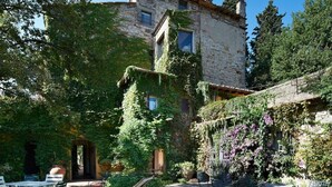 A rustic stone building with ivy-covered walls, outdoor seating, and gravel ground. - I Parigi Corbinelli (Florence)