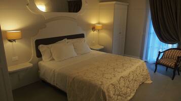 A bedroom with a large bed, two bedside lamps, a wardrobe, and a chair.