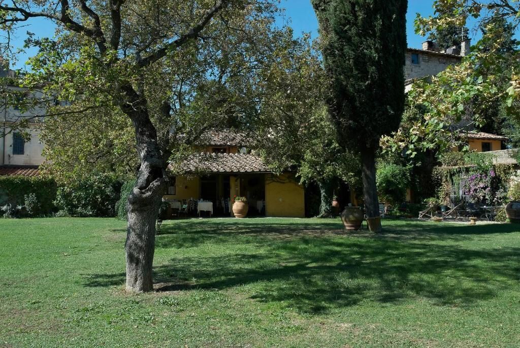 A rustic villa with a tiled roof, surrounded by lush greenery and trees.