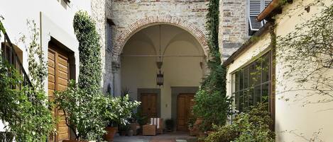 A narrow stone pathway leading to a historic building with a stone facade and a small arched entrance.